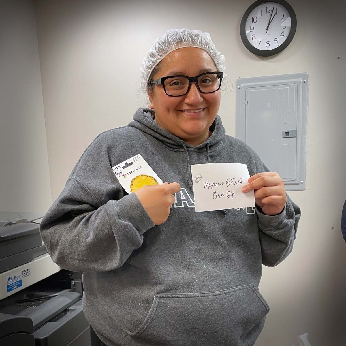 Joanna holding up her Mexican Street Corn Dip sign and the grocery gift card she won.