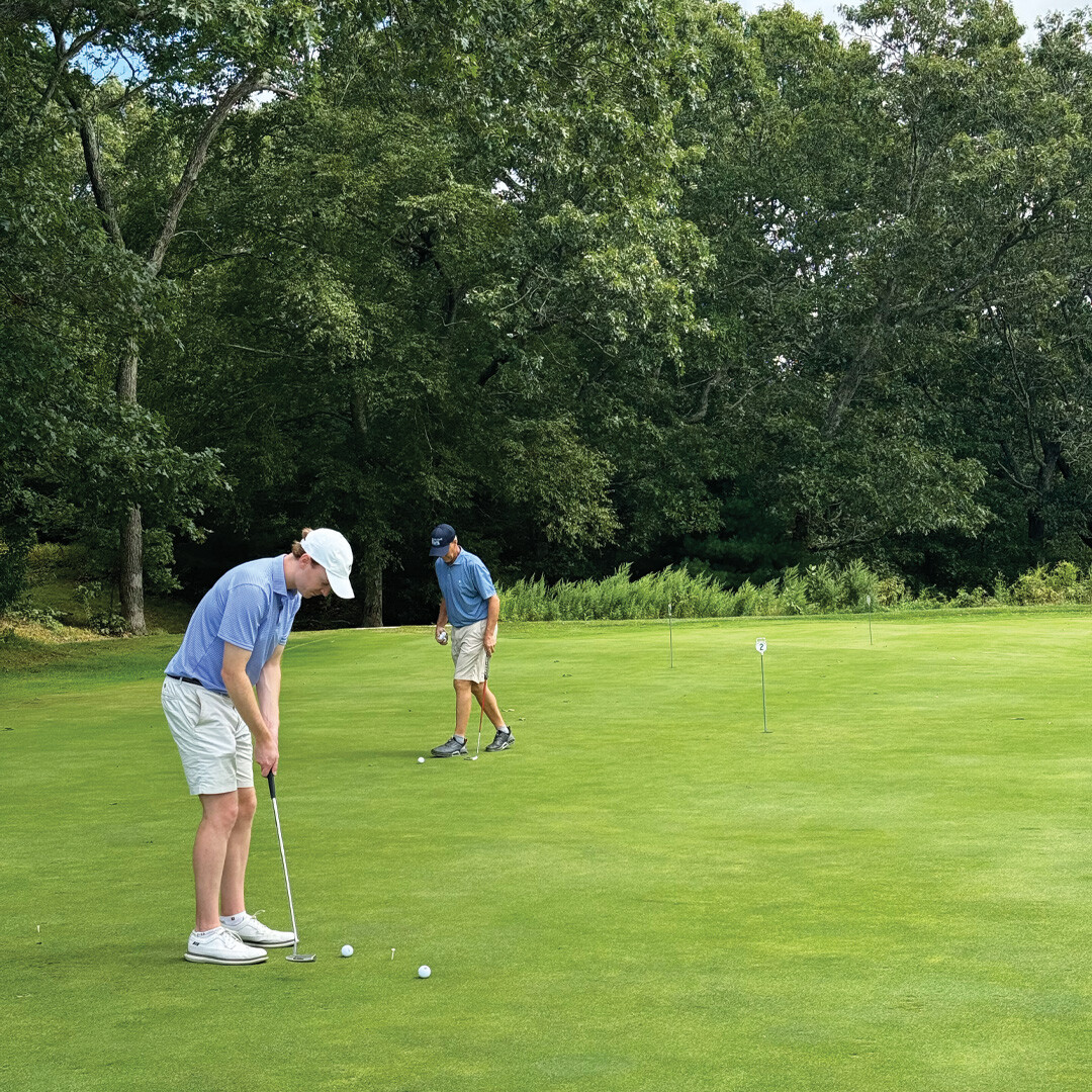 Hero of Town Dock employees putting at the putting contest hole at the golf tournament.